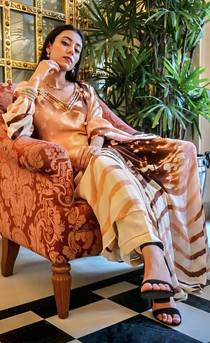 The kurta is paired with comfortable ivory palazzos and the set completes with a gorgeous flowy chinon chiffon silk dupatta, with handmade buttoned detail on its hemline.