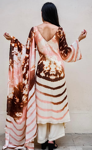 The blend of abstract dye on the top with accents of blush, copper and rust, represents the colourful sunsets of Mykonos balancing with the calming waves at the bottom half. The sleeves and the dupatta carry the same twin dye technique as the Kurta.