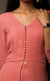 The muse here is wearing a simple and elegant front-slit dress with palazzos in carrot pink. The dress comprises of an upper yoke and a simple v-neckline which is further having a vertical buttoned detail on yoke and a high slit in the middle center. It is further paired with cupro georgette flowy wide legged palazzos.