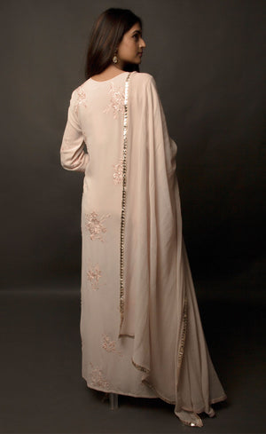 Dusty Rose side slit suit set, crafted in georgette, fully embroidered with signature flat threadwork topped with sequins spray accompanied by a dupatta with rose gold mukaish border. The ensemble carries a strong of a confident style because of the slim straight trousers underneath, the bottom of the trousers is finished by our signature buttoned hemline style. Flaunt your chic style in this elaborately worked ensemble, the muse radiates a modern, yet classic vibe.
