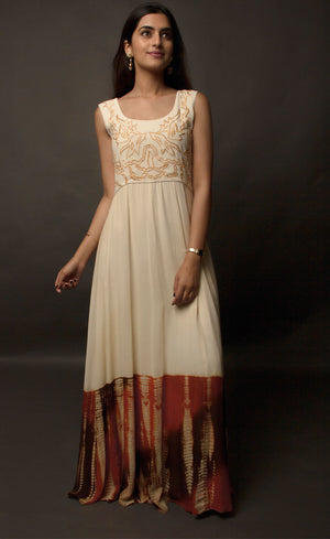 This particular ivory dress in georgette carries a series of thin beautiful long floor length panels from waist down, the yoke is embroidered with a rust colour thread-work, the front and back of the yoke is embroidered with an intentional different pattern, the back yoke embroidery is more prominent and dense than the front. The knee down has been treated with hand tie and dye Batik technique in deep rust and brown accents over the ivory base.