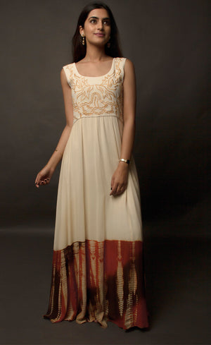 This particular ivory dress in georgette carries a series of thin beautiful long floor length panels from waist down, the yoke is embroidered with a rust colour thread-work, the front and back of the yoke is embroidered with an intentional different pattern, the back yoke embroidery is more prominent and dense than the front. The knee down has been treated with hand tie and dye Batik technique in deep rust and brown accents over the ivory base. 