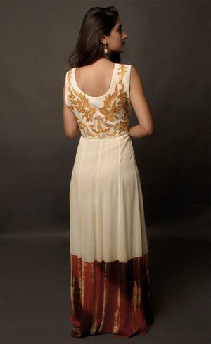 This particular ivory dress in georgette carries a series of thin beautiful long floor length panels from waist down, the yoke is embroidered with a rust colour thread-work, the front and back of the yoke is embroidered with an intentional different pattern, the back yoke embroidery is more prominent and dense than the front. The knee down has been treated with hand tie and dye Batik technique in deep rust and brown accents over the ivory base. 