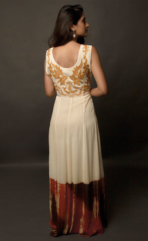This particular ivory dress in georgette carries a series of thin beautiful long floor length panels from waist down, the yoke is embroidered with a rust colour thread-work, the front and back of the yoke is embroidered with an intentional different pattern, the back yoke embroidery is more prominent and dense than the front. The knee down has been treated with hand tie and dye Batik technique in deep rust and brown accents over the ivory base.