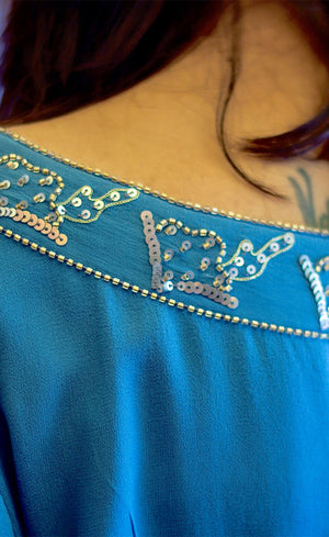 All eyes will be on you in this mykonos blue, exquisitely detailed one off shoulder dress. This dress features an elegant and effortlessly trendy one off shoulder neckline, carefully embroidered with beads and sequins giving a subtle and sophisticated look that exudes glamour. It has full sleeves that are gathered around the cuff, slightly ruched drawstring insertion along the waistline and a high slit at one of it's sides making this dress suitable for any occasion.