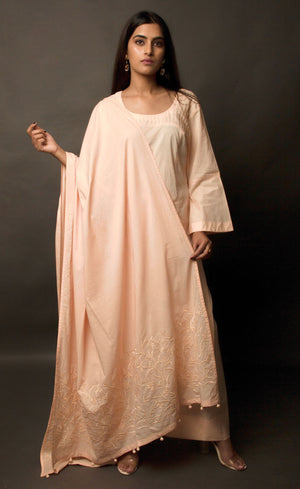 The muse here is wearing a peach embroidered kurta suit set. This is a 100% cotton suit with panelled kurta having lace insertions in the vertical panels and pin tucks in the upper yolk. The kurta is enhanced with flared sleeves having single horizontal lace insertion around the elbow. It is paired with a flared cotton palazzos and a cotton dupatta with our signature thread-work embroidery along its width, further finished with a buttoned detail. 