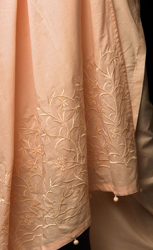 The muse here is wearing a peach embroidered kurta suit set. This is a 100% cotton suit with panelled kurta having lace insertions in the vertical panels and pin tucks in the upper yolk. The kurta is enhanced with flared sleeves having single horizontal lace insertion around the elbow. It is paired with a flared cotton palazzos and a cotton dupatta with our signature thread-work embroidery along its width, further finished with a buttoned detail. 