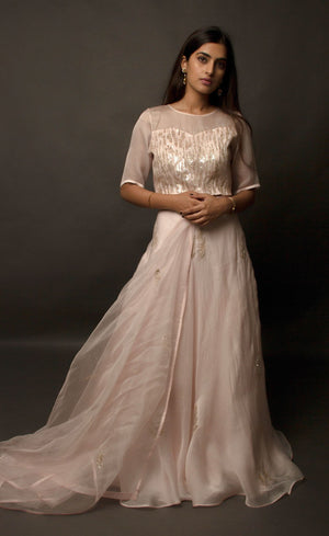 This dirty pale pink satin organza lehenga skirt is embroidered with zari and sequins motifs, the top is embellished with linear sequins and the coordinating silk organza dupatta is embroidered with sequin motifs finished with a raw silk border.