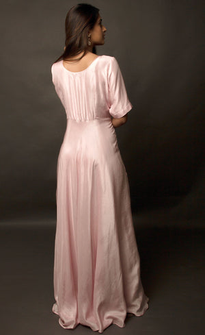 Graceful, demure and classic simplicity, this powder pink ensemble features a geometric hand embroidery on the mid yoke of this floor length flowing gown. Adorned with understated combination of peachy and translucent beads and threads, this cupro satin piece is yet a delicately detailed silhouette.