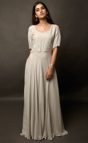 Steel grey flared gown, with beautiful sleeves achieved by handmade sequin buttons - a personal detail that only the wearer can experience, the gown is embroidered with signature thread-work further highlighted by sequins on the front yoke. This flowing gown set in a neutral palette entails a beautifully weightless flare, allowing you to express more freedom of movement.