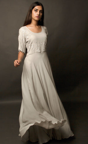 Steel grey flared gown, with beautiful sleeves achieved by handmade sequin buttons - a personal detail that only the wearer can experience, the gown is embroidered with signature thread-work further highlighted by sequins on the front yoke. This flowing gown set in a neutral palette entails a beautifully weightless flare, allowing you to express more freedom of movement.