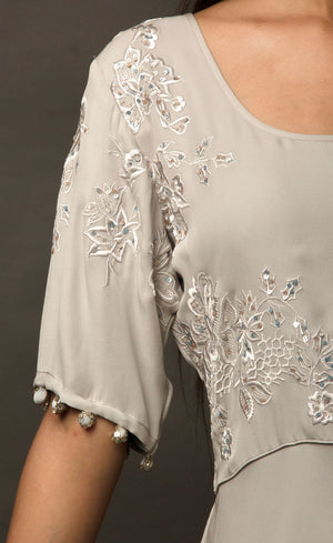 Steel grey flared gown, with beautiful sleeves achieved by handmade sequin buttons - a personal detail that only the wearer can experience, the gown is embroidered with signature thread-work further highlighted by sequins on the front yoke. This flowing gown set in a neutral palette entails a beautifully weightless flare, allowing you to express more freedom of movement.
