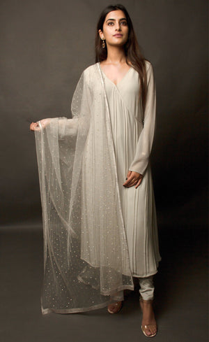 This angrakha in steel grey is highlighted with vertical pin-tucks all across the kurta. It is paired with a minimally sequin sprayed tulle fine net dupatta, that is further finished with a raw silk border. The look is completed with a stretch crepe churidaar / slim pants.