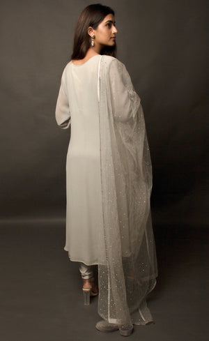 This angrakha in steel grey is highlighted with vertical pin-tucks all across the kurta. It is paired with a minimally sequin sprayed tulle fine net dupatta, that is further finished with a raw silk border. The look is completed with a stretch crepe churidaar / slim pants.