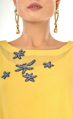 The muse here is wearing our sunflower yellow cape dress crafted in cupro georgette. Elegant and effortlessly trendy, this cape dress will keep you looking fabulous all day and night. This dress accompanies a slightly fitted inner silhouette, a fashion-forward cape embroidered with deep blue beads and sequins making it an elegant resort and holiday lounge style and a subtle back.