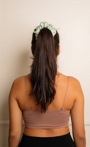 Person wearing a brown sports bra and black leggings with a neutral background