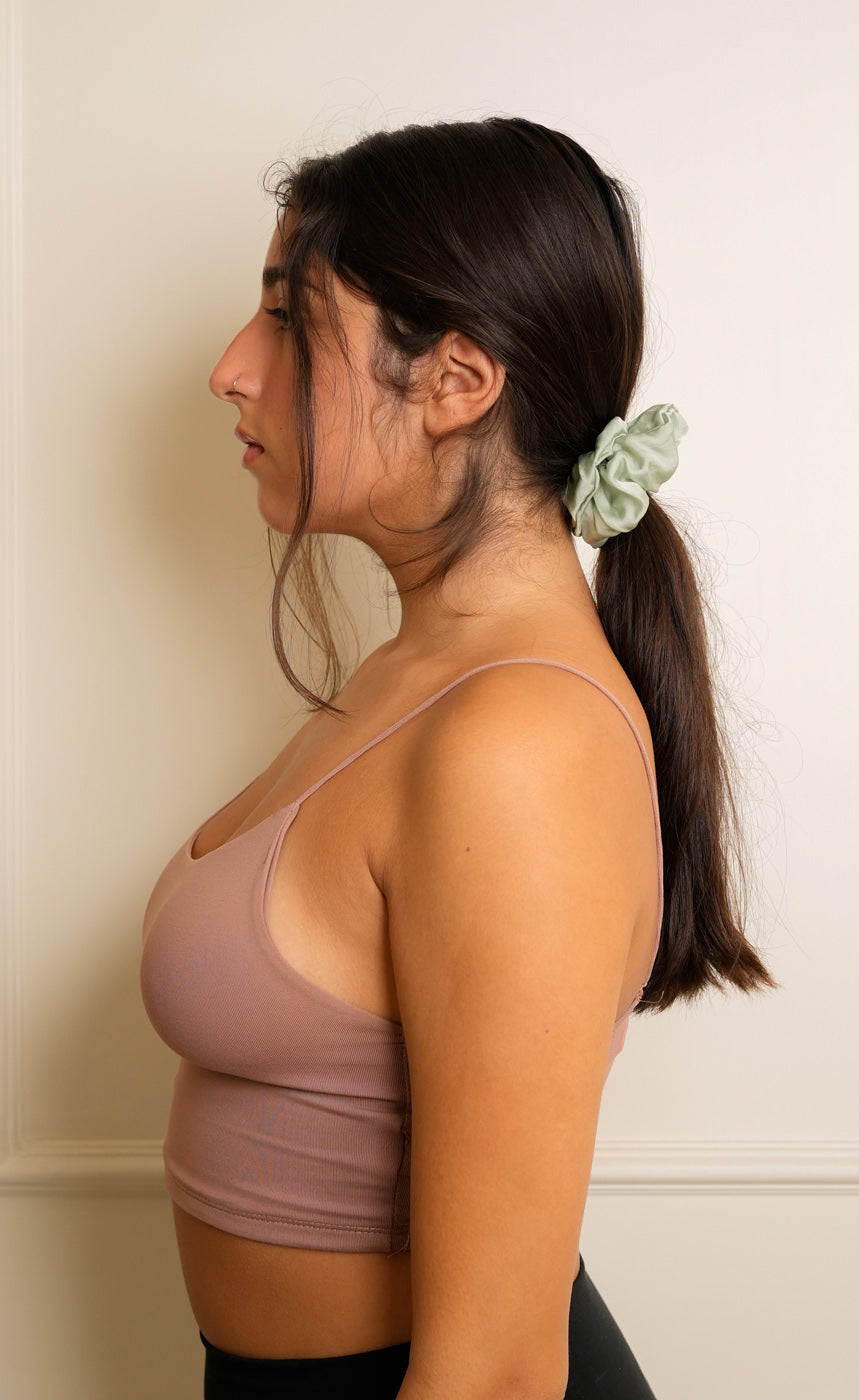 Person wearing a brown sports bra and black leggings with a neutral background