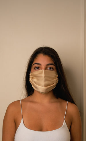 Woman wearing a beige face mask against a plain background