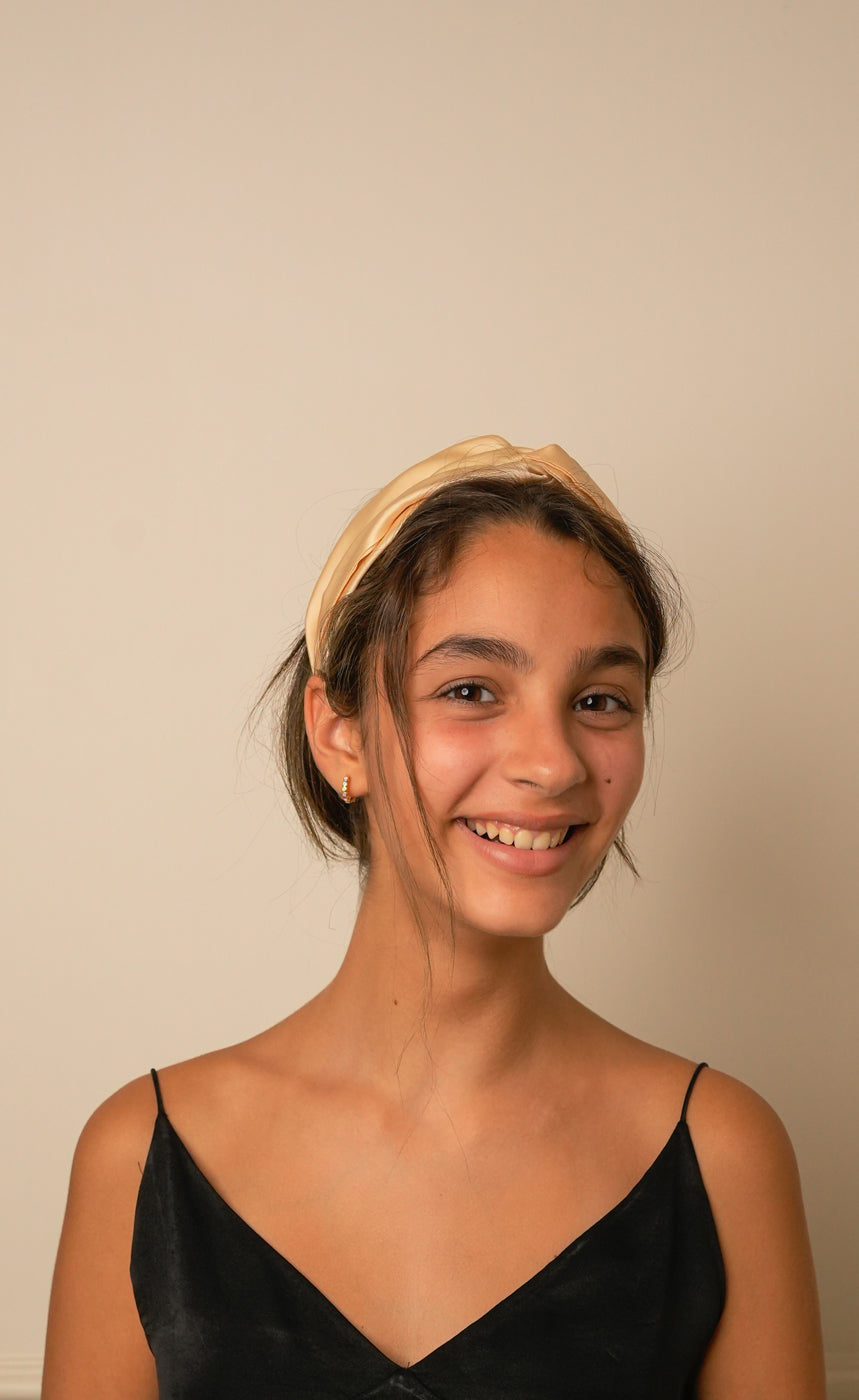 Beige Bemberg satin knotted headband worn by woman front view — Jasmine Bains handcrafted hair accessory