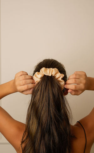 Woman adjusting Beige satin headband from behind, showing knot detail