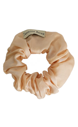 Beige satin scrunchie with a brand tag on a white background