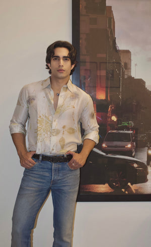 Man wearing a light-colored shirt and jeans standing in front of a movie poster with a city street scene.