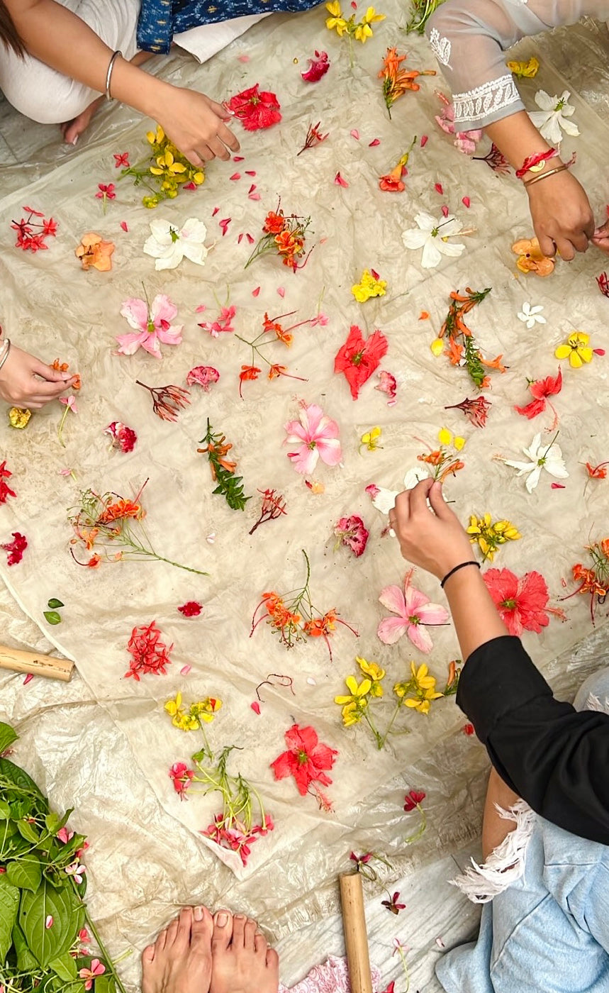 Participants arranging fresh botanicals - hibiscus, cosmos, marigold, and delicate wildflowers - on silk fabric during a Jasmine Bains eco-printing workshop in Chandigarh 