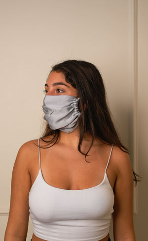 Woman wearing a grey face mask against a plain background