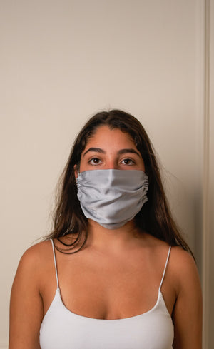 Woman wearing a light gray face mask against a plain background