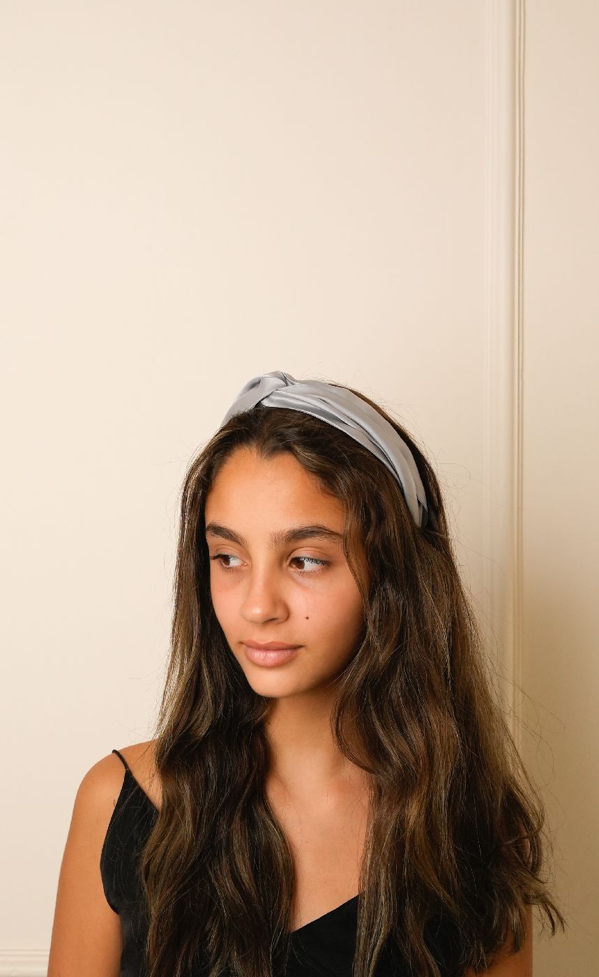 Woman wearing a light blue headband against a neutral background