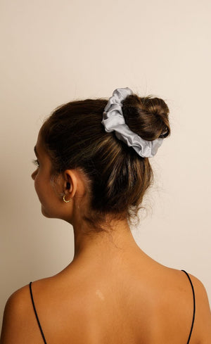 Person with a scrunchie in their hair against a beige background