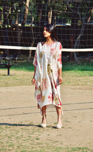 Woman in a floral dress standing on a tennis court