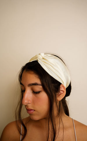Ivory satin knotted headband worn with sleep mask pushed up, close-up profile view