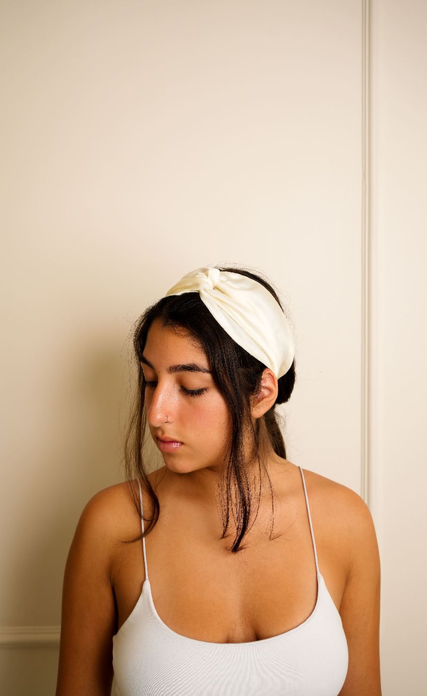 Ivory Bemberg satin knotted headband worn by woman front view — Jasmine Bains handcrafted hair accessory