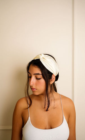 Woman wearing a white headband against a plain background