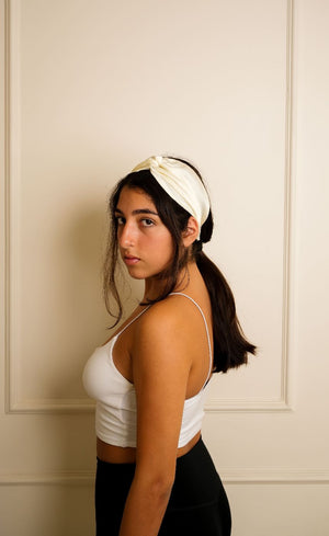 Woman wearing a white headband against a neutral wall
