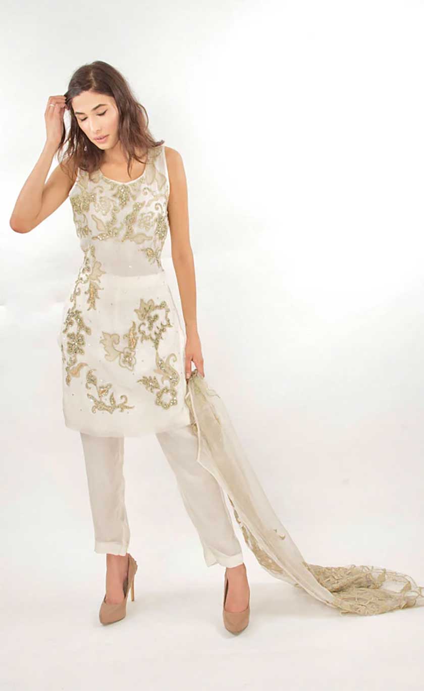 Woman wearing a white dress with gold embellished embroidery on a white background