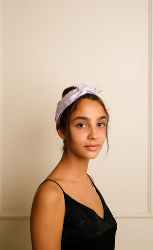 Woman wearing a purple headband against a beige wall