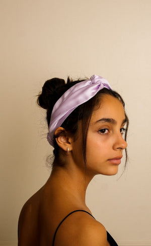 Woman wearing a light purple headband against a beige background