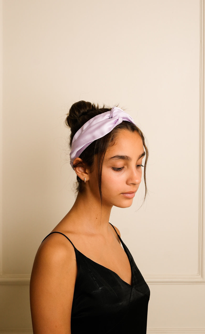 Woman wearing a light purple headband against a neutral background