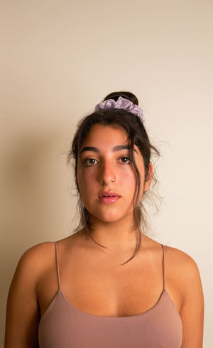 Woman wearing a beige tank top against a plain background