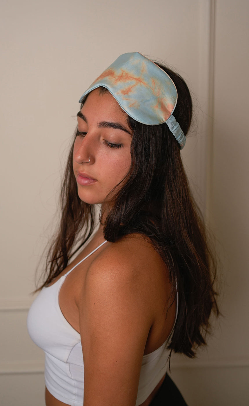 Tie-dye hair accessories including a headband, scrunchies, and a paddle on a tie-dye fabric background.