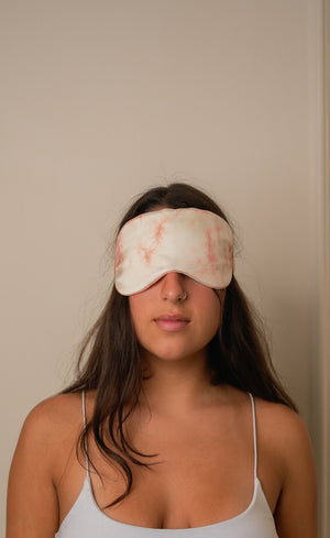 Woman wearing a floral sleep mask against a plain background