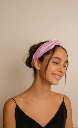 Woman wearing a pink headband against a beige background