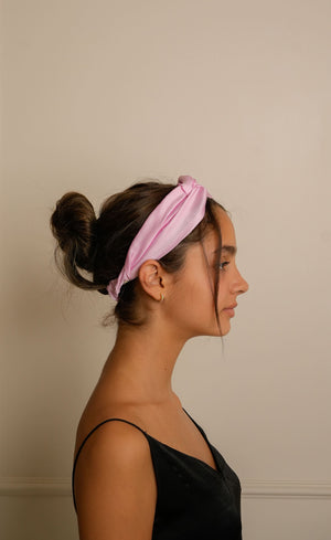 Woman wearing a pink headband against a plain background