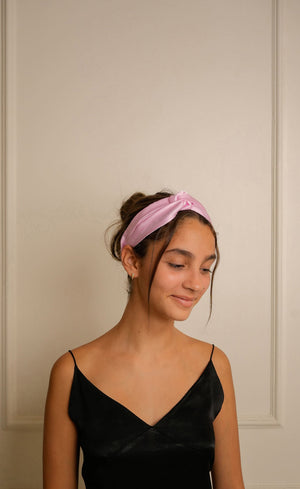 Woman wearing a beautiful pink satin headband with a smooth, glossy finish. 