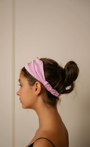 Woman wearing a high quality pink headband against a plain background