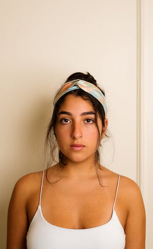 Woman wearing a blue tie and dye marble print headband against a beige wall