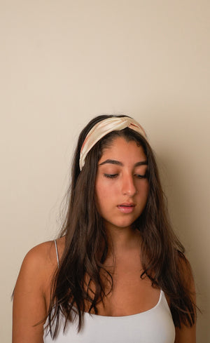 Woman wearing a tie and dye beige headband against a plain background