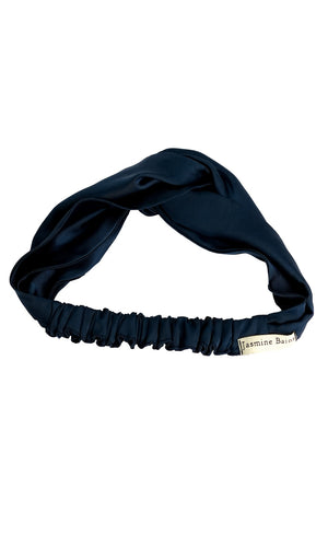 Navy blue headband with a brand label Jasmine Bains on a white background